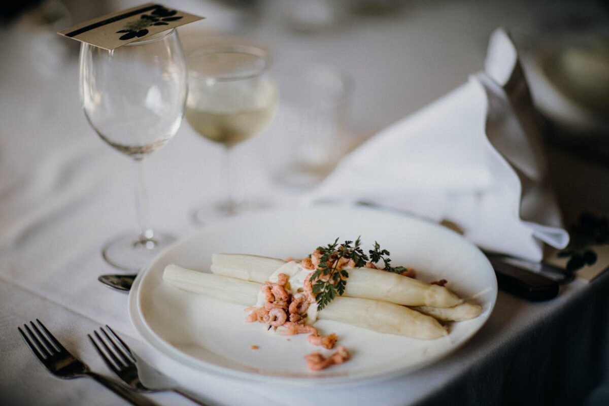 A gourmet asparagus plate with garnish on a table set for fine dining.
