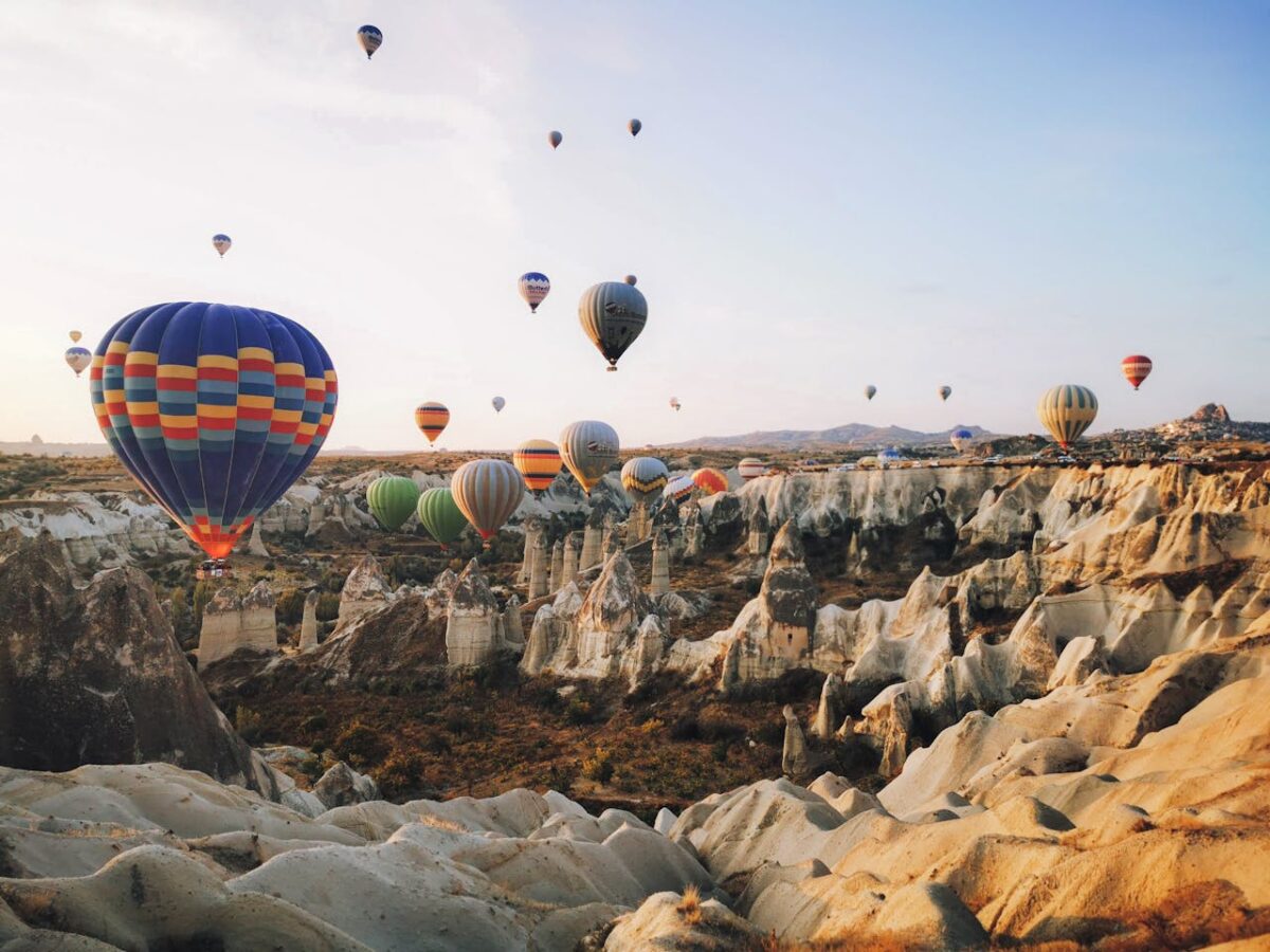 services-01 Colorful hot air balloons floating over Cappadocia's unique rock formations at sunrise.